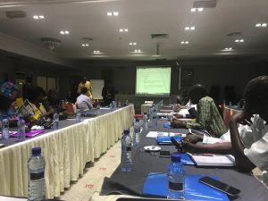 A picture of the room of the conference. People are listening to a presentation