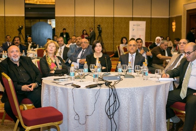 People sitting at a table, listening to a presentation